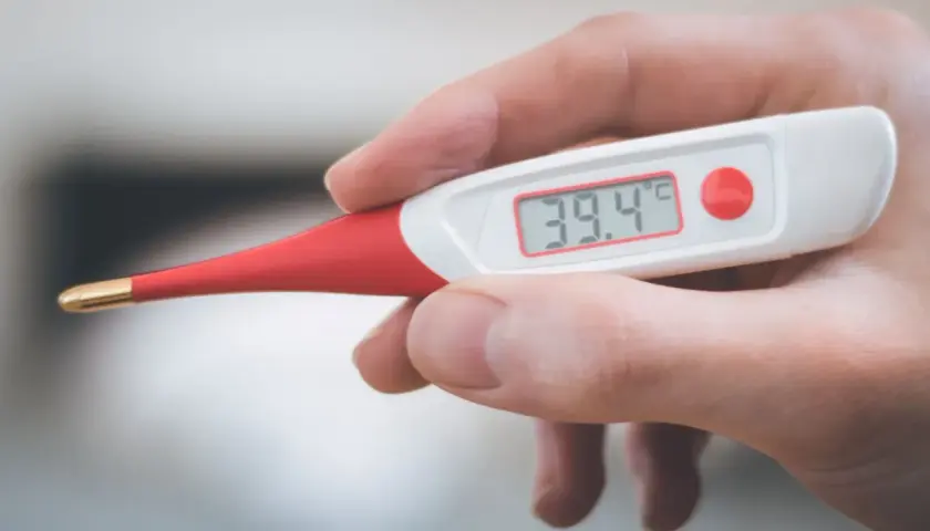 Dłoń trzyma termometr cyfrowy pokazujący 39.4°C. To może oznaczać gorączkę u psa, który potrzebuje pomocy weterynarza.