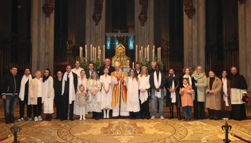 Gruppe feiert den Osternacht Gottesdienst mit Bischof in festlicher Robe vor Kerzenlicht und Altar.