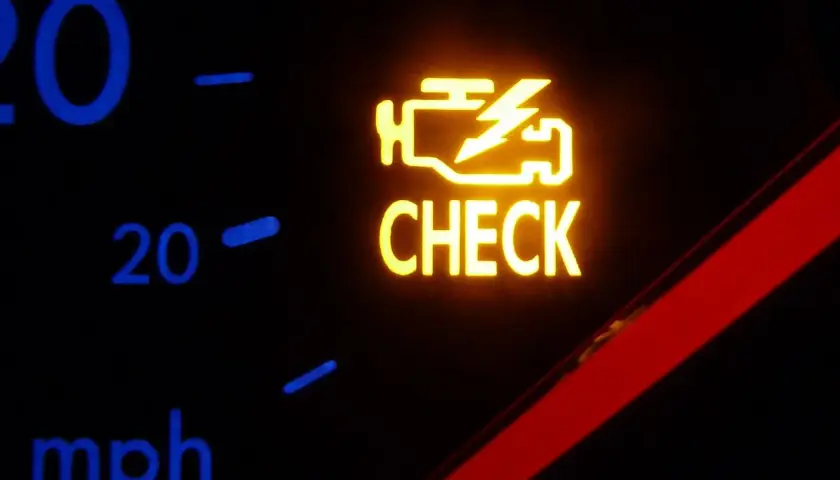 Żółta kontrolka silnika z napisem "CHECK" na desce rozdzielczej samochodu.