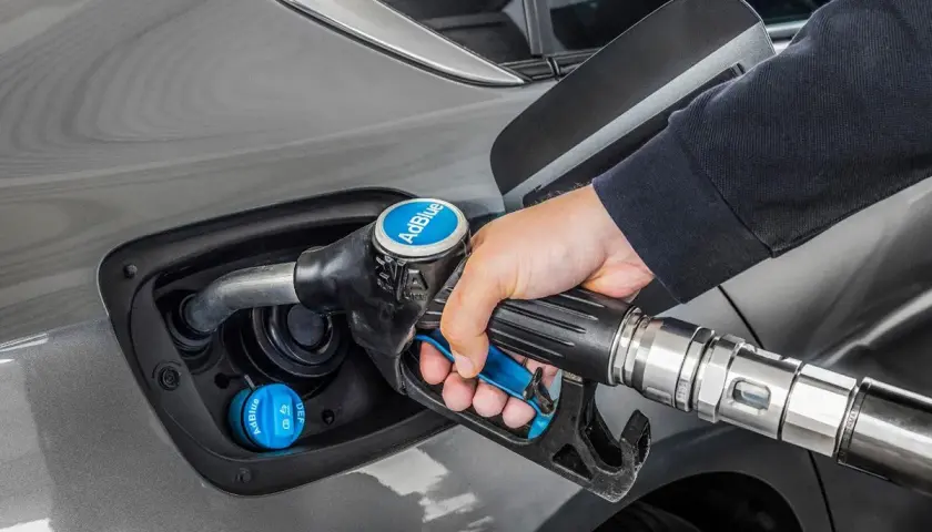Persona repostando AdBlue en su coche. La cantidad de kilómetros que dura el AdBlue varía según el vehículo y el estilo de conducción.