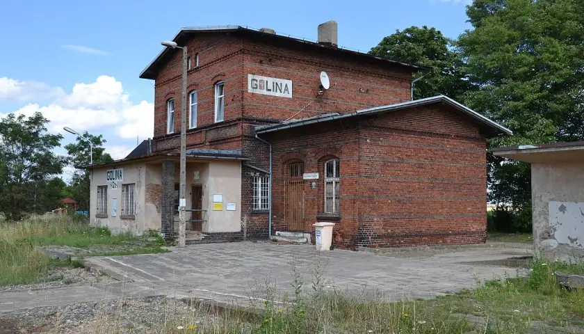 Stary ceglany budynek dworca kolejowego Golina z napisem "GOLINA" na fasadzie.