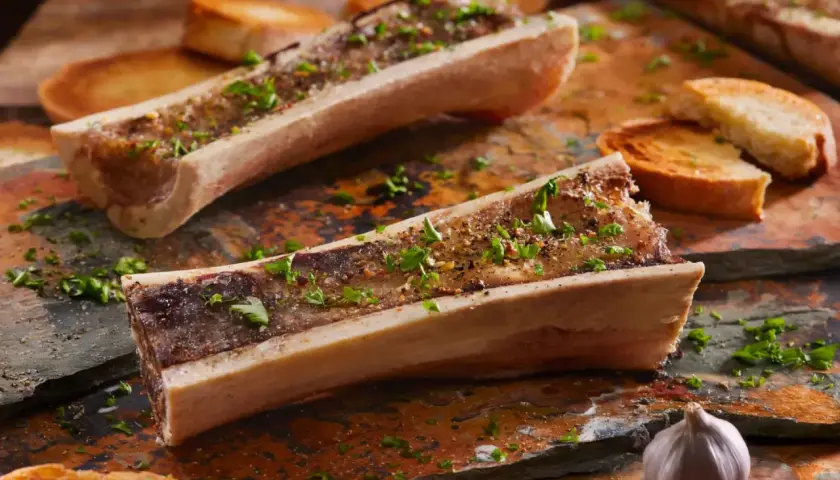 Os à moelle au barbecue, assaisonnés d'herbes et servis avec des toasts grillés et de l'ail. Un délice à savourer !