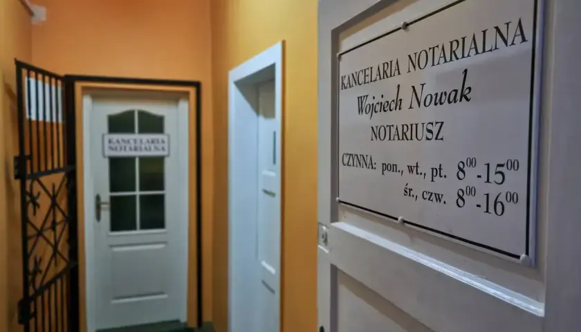 Tabliczka z nazwą kancelarii notarialnej Wojciecha Nowaka i godzinami otwarcia.