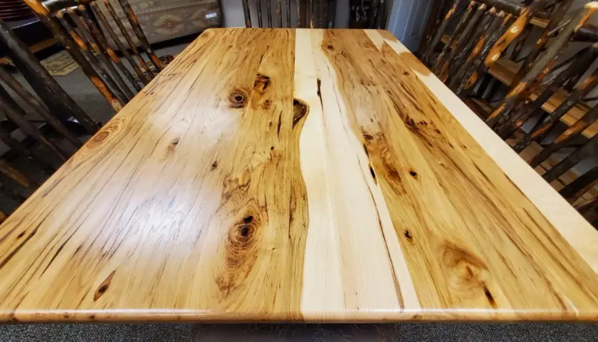 A rustic dining table crafted from the prettiest wood, showcasing natural grain patterns and knots. Chairs with twig-like legs surround it.