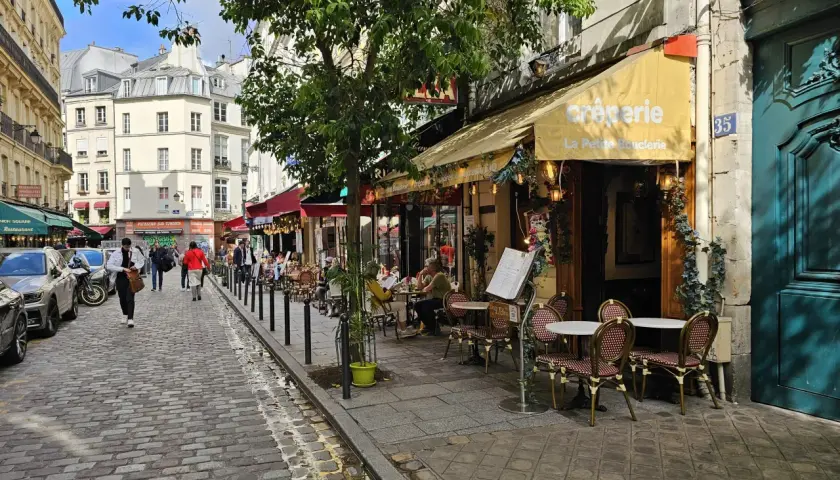 Ulica w dzielnicy łacińskiej Paryża z kawiarnią "La Petite Boulangerie" i brukowanym chodnikiem.
