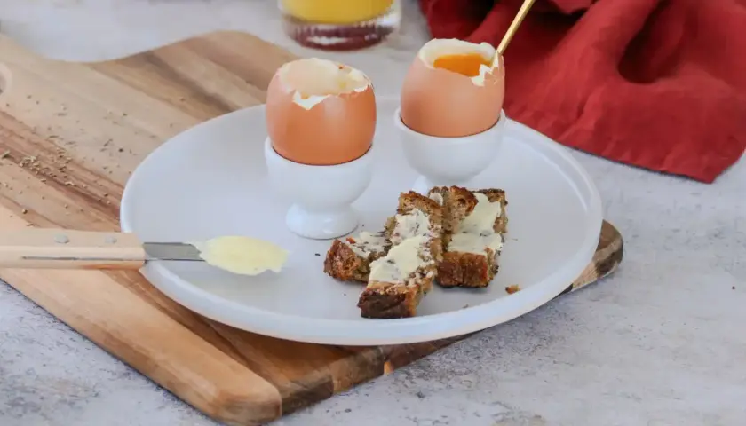 Deux oeufs à la coque, prêts à être dégustés avec des mouillettes de pain beurrées. Un petit-déjeuner simple et réconfortant.