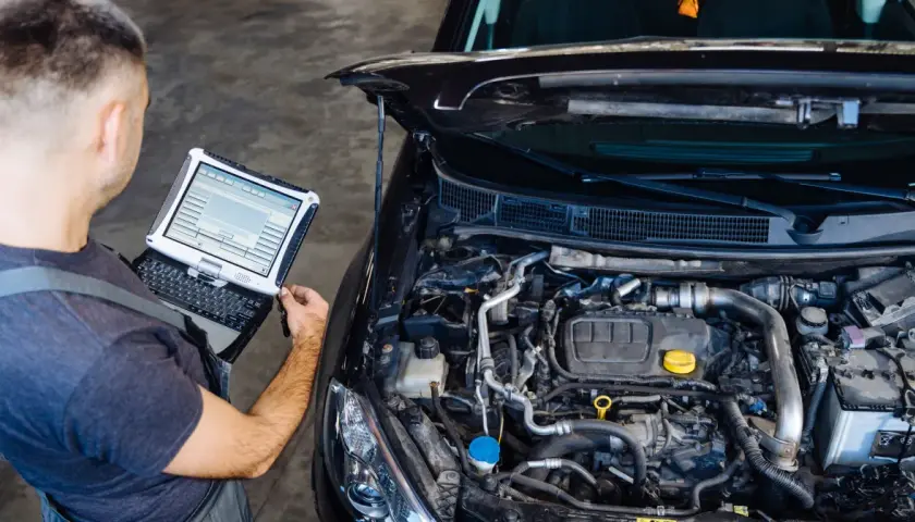 Mechanik diagnozuje przedmuchy w silniku za pomocą komputera.