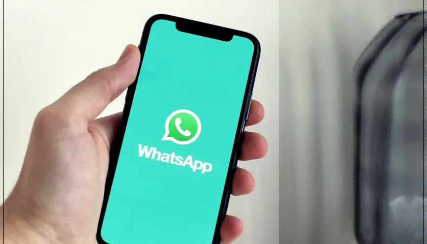Dłoń trzyma smartfon z logo WhatsApp. Dowiedz się, jak dzwonić bez karty SIM, korzystając z tej popularnej aplikacji.