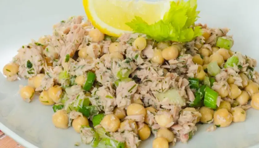 Insalata di ceci e tonno, fresca e saporita, guarnita con limone e sedano.