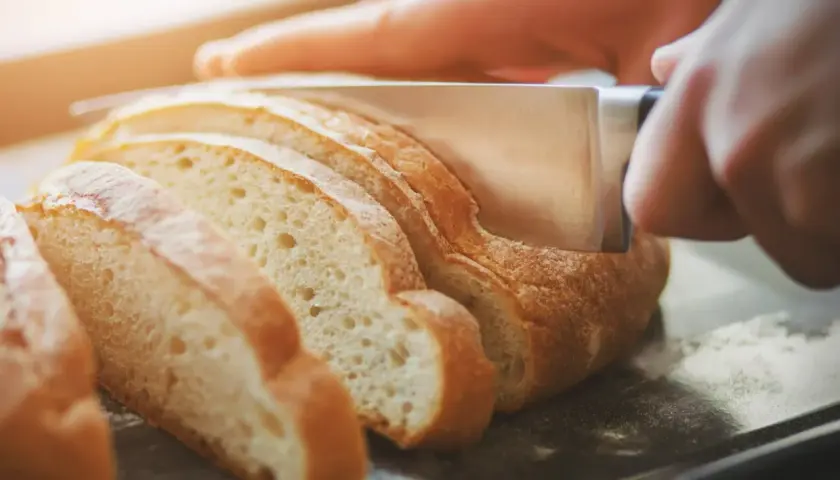 Krojony chleb na desce, gotowy, by dowiedzieć się, jak podgrzać chleb w piekarniku.