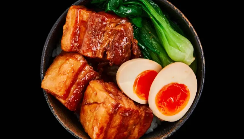 A bowl of Japanese pork belly with rice, bok choy, and a soft-boiled egg.