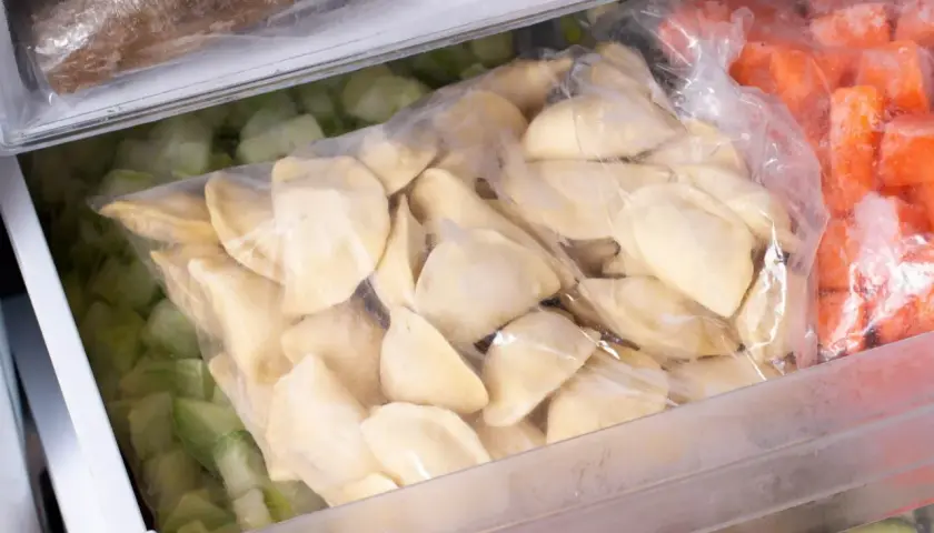 Jak mrozic domowe pierogi? W zamrażarce leżą woreczki z pierogami, mrożonymi warzywami i innymi produktami.
