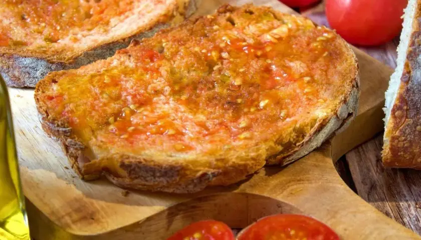 Rebanadas de pan tostado con tomate rallado y aceite de oliva, un delicioso pan de tomate listo para disfrutar.