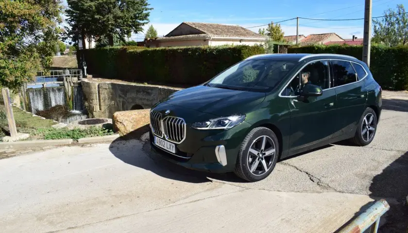 Un BMW Serie 2 Active Tourer verde oscuro aparcado cerca de una esclusa de agua. ¿Problemas con el coche o solo una parada escénica?