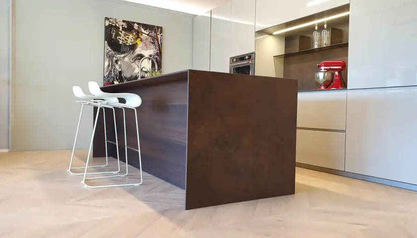 Moderno montaggio cucina con isola centrale in legno scuro, sgabelli bianchi e quadro artistico.