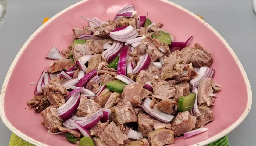 Salade de viandes froides, un plat savoureux avec des morceaux de viande, des oignons rouges et des avocats, servi dans un bol rose.