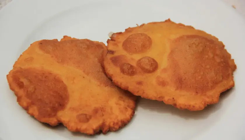 Dos tortos asturianos dorados y crujientes sobre un plato blanco.