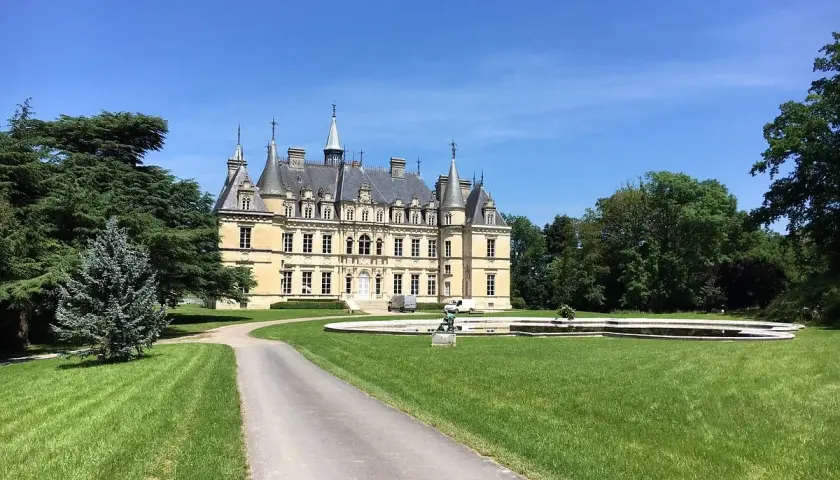 Château majestueux sous un ciel bleu, avec une allée menant à l'entrée. Un lieu idéal pour déguster un champagne Le Gallais.
