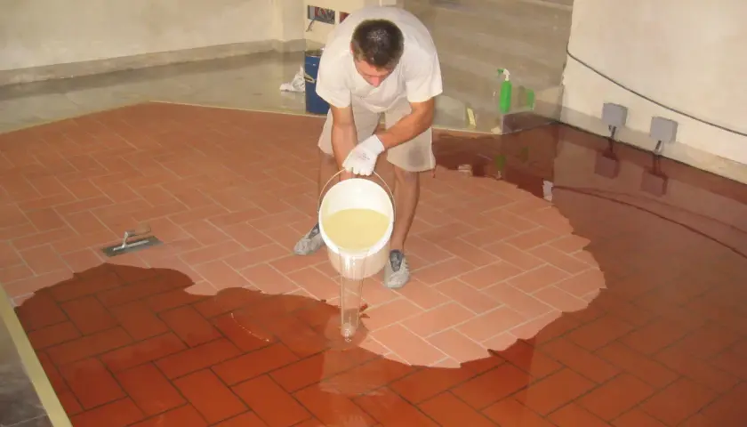 Uomo versa resina per coprire piastrelle cucina, creando una superficie lucida e moderna.