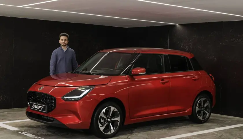 Hombre posando junto a un Suzuki Swift rojo brillante, listo para su prueba.