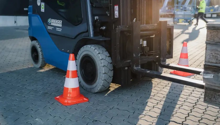 Ein Gabelstapler steht bereit, um zu stapler fahren. Orangefarbene Verkehrskegel markieren den Bereich.