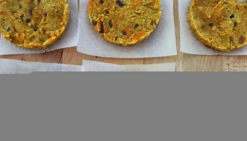 Seis hamburguesas de lentejas caseras, listas para cocinar. Tienen trocitos de zanahoria y cebolla morada.