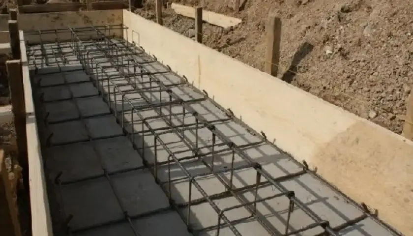 Siatka zbrojeniowa w deskowaniu fundamentu. Widać regularny układ, co ile strzemiona na fundament, gotowe do zalania betonem.