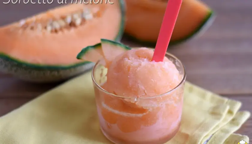 Sorbetto al melone rinfrescante in un bicchiere, con fette di melone fresco sullo sfondo.