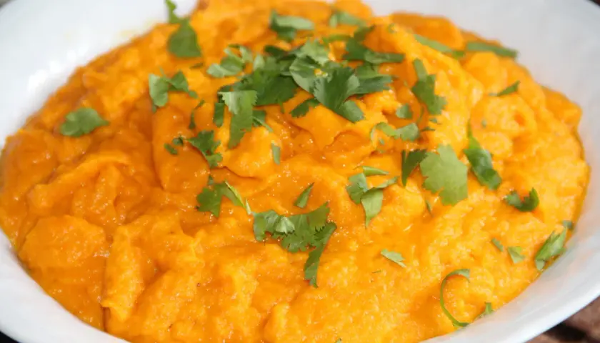 Purée de carotte onctueuse, garnie de feuilles de coriandre fraîche. Un délice orangé et savoureux.