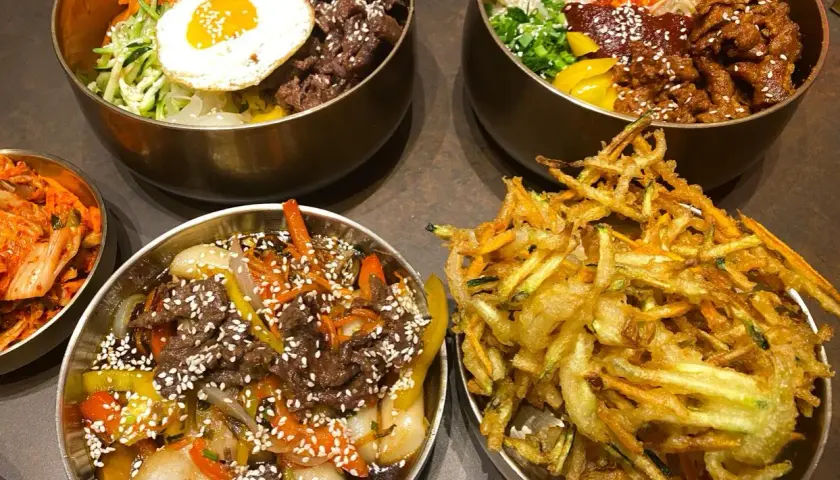 Pyszne dania koreańskie, w tym bibimbap i smażone warzywa, idealne dla szukających najlepszych restauracji w Poznaniu.