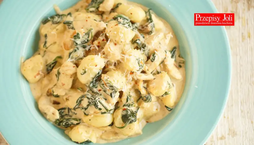 Pyszne gnocchi z kurczakiem i szpinakiem w kremowym sosie, posypane parmezanem. Idealne danie na szybki obiad.