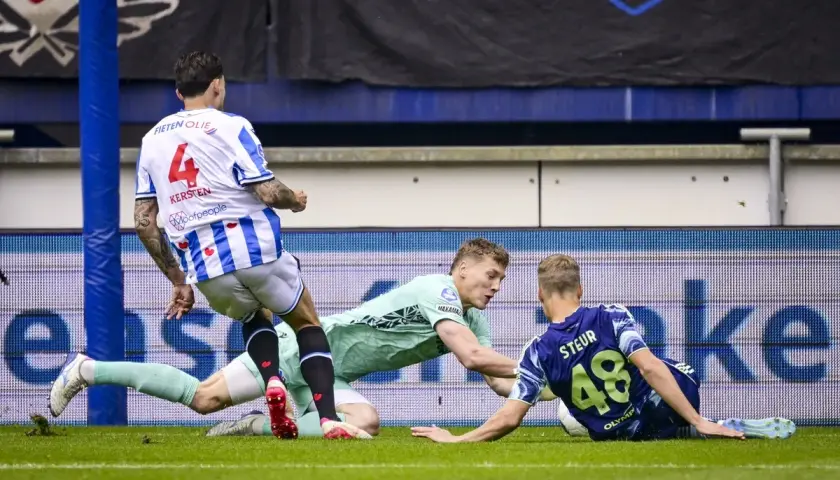 Piłkarze walczą o piłkę na boisku. Jeden z nich leży na ziemi, próbując ją odebrać. To zacięta akcja, która może wpłynąć na pozycję w **liga holenderska tabela**.