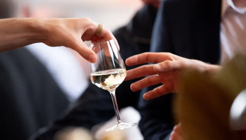 Des mains échangent un verre de vin blanc lors d'une dégustation à Angers.