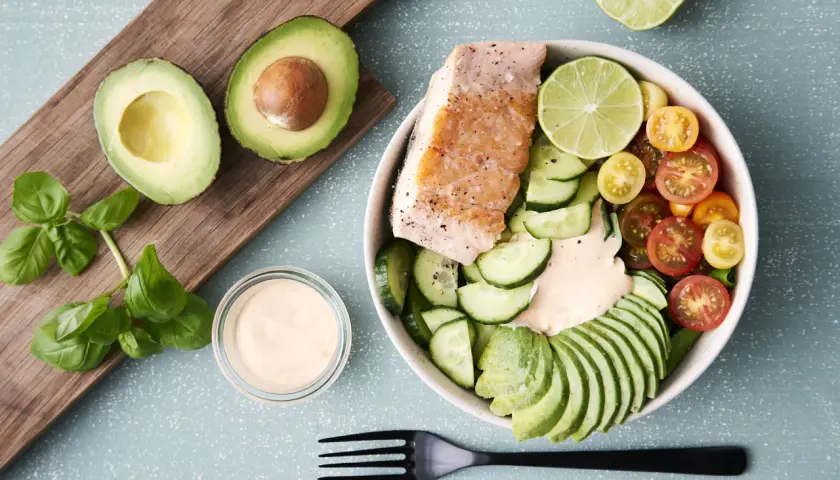 En härlig keto recept-bowl med lax, avokado, gurka, tomater och en krämig dressing. Perfekt för en hälsosam lunch.