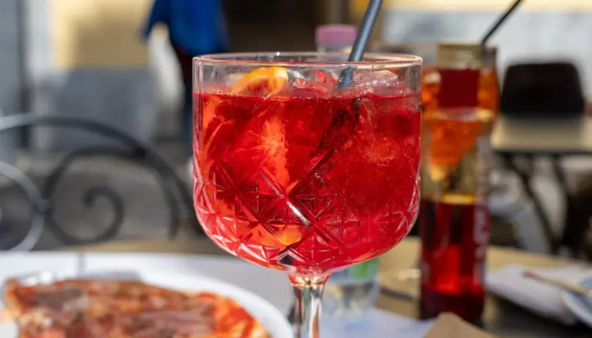 Orzeźwiający Aperol Spritz z plastrem pomarańczy, idealny na aperitivo. Pytasz gdzie zjeść w Mediolanie? To może być początek Twojej kulinarnej podróży!