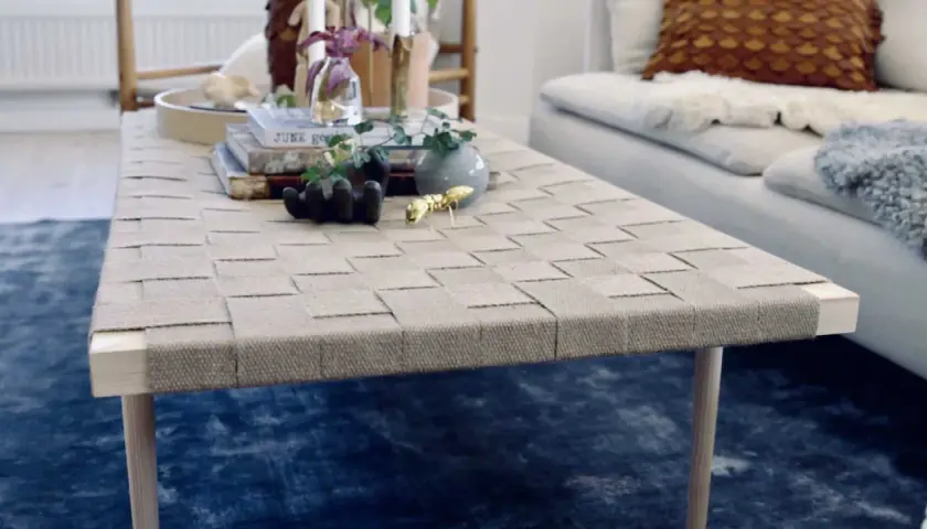 Ett vackert diy soffbord med flätad topp och träben. Prydnader som en guldfärgad myra och en liten vas ger liv åt bordet.