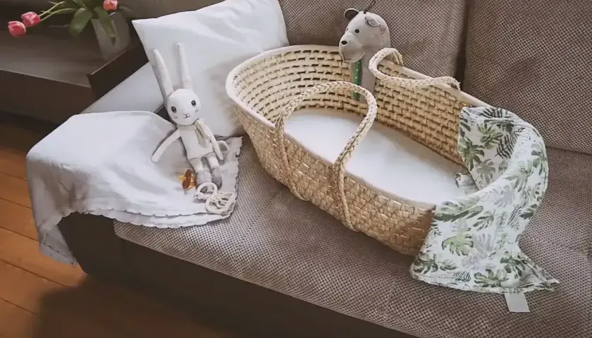 Uroczy koszyk mojżesza z pluszowym zajączkiem i kocykiem w liście, gotowy na przyjęcie maluszka.