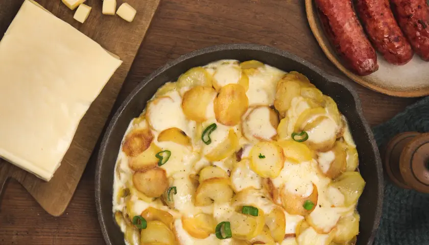 Plat gratiné de pommes de terre et fromage fondant, parfait pour une recette diots de Savoie. Accompagné de saucisses savoureuses.