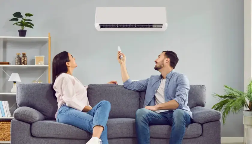 Pareja disfrutando del confort de su hogar con un aire acondicionado que ofrece un boost de aire fresco.