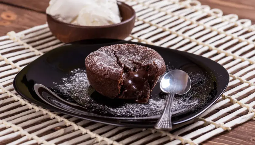 Un délicieux moelleux au chocolat, cœur coulant, saupoudré de sucre glace, servi avec de la glace à la vanille. Une recette gourmande à tester !