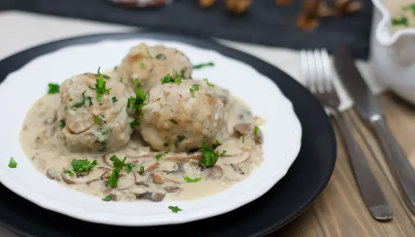 Vegane Semmelknödel in cremiger Pilzrahmsoße, garniert mit frischer Petersilie. Ein herzhaftes Gericht, das Lust auf mehr macht.