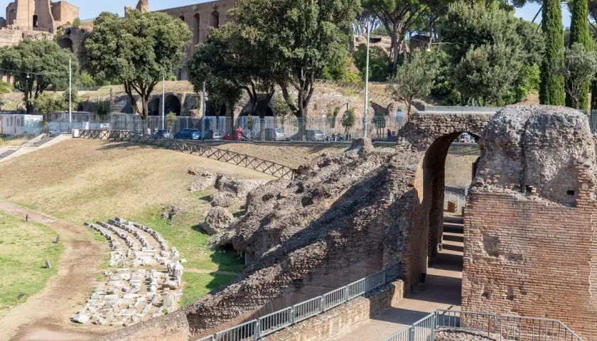 Ruines antiques du Circo Massimo à Rome, avec des gradins en pierre et une arche de briques menant à des escaliers.