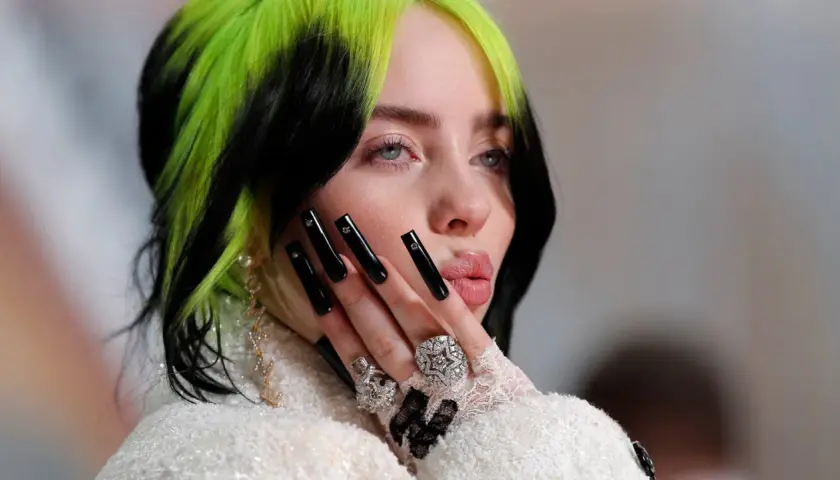 Billie Eilish z zielono-czarnymi włosami i długimi czarnymi paznokciami, przypominająca styl z piosenki "Nie czas umierać".