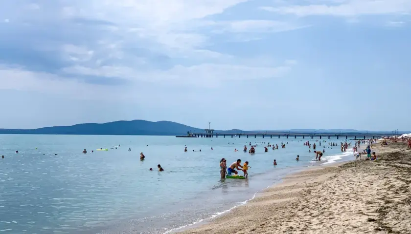 Plaża w Burgas, mnóstwo ludzi kąpiących się i opalających. Długie molo, góry w tle. Burgas czy warto? Zdecydowanie tak!