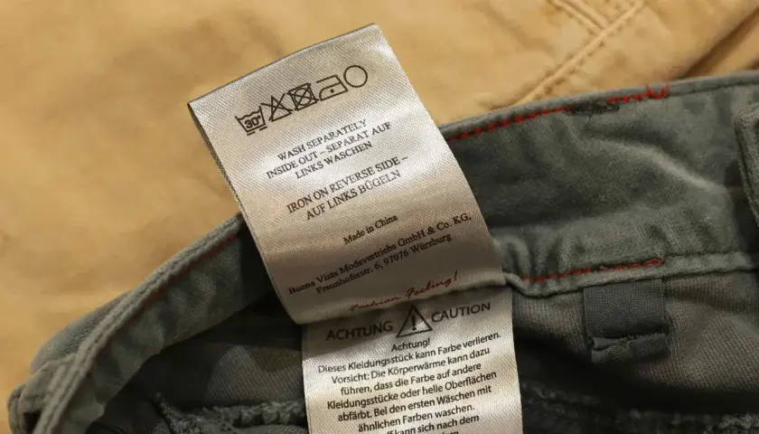 Pflegeetikett einer Jeans: separat in der Waschmaschine waschen, auf links bügeln.