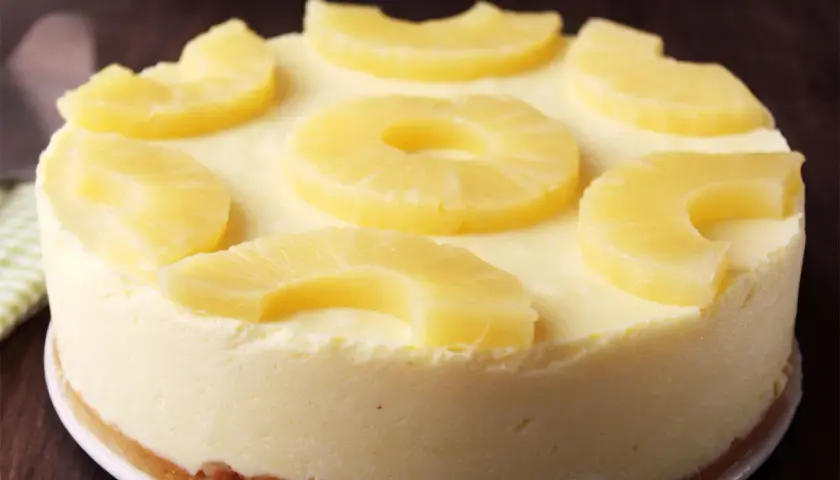 Tarta de piña cremosa, decorada con rodajas y trozos de piña fresca. Un postre tropical irresistible.