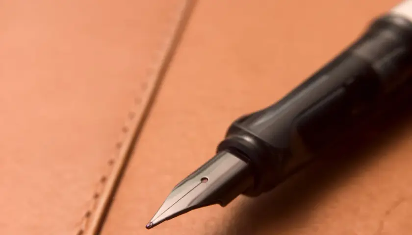 Plume d'un stylo plume noir sur un cuir brun. Une question se pose : comment enlever du stylo sur du cuir ?