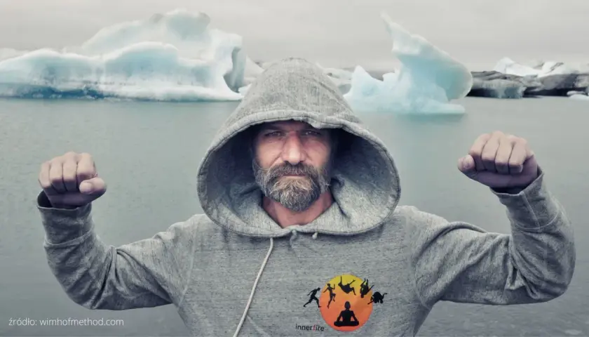 Wim Hof w szarej bluzie z kapturem, z zaciśniętymi pięściami, na tle lodowca. Siła i hart ducha.