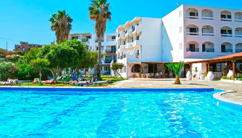 Basen i białe budynki hotelowe z palmami. Wiele osób odpoczywa na leżakach. Ocean Heights View Hotel opinie - idealne miejsce na wakacje.