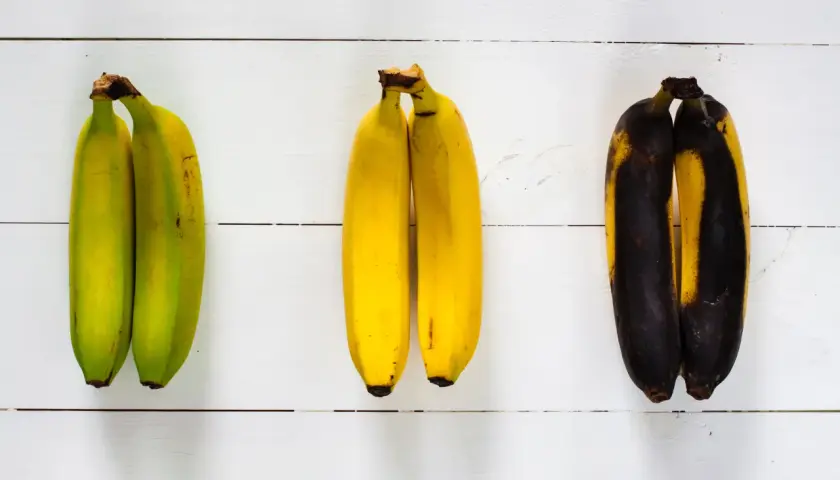 Drei Paare Bananen: links unreif grün, in der Mitte reif gelb, rechts überreif schwarz.